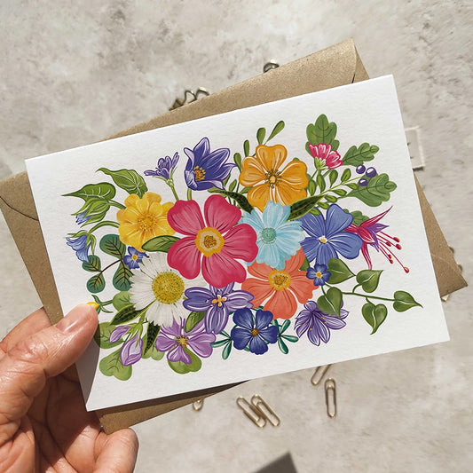 Colorful floral card held by a hand on a neutral background