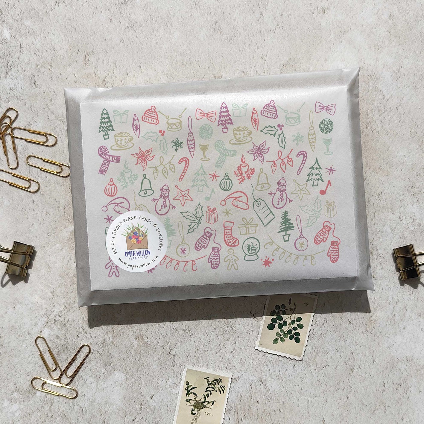 Gift box with decorative paper featuring Christmas illustrations on a light gray surface.