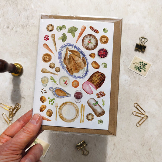 Greeting card with food illustrations held by a hand on a textured surface.