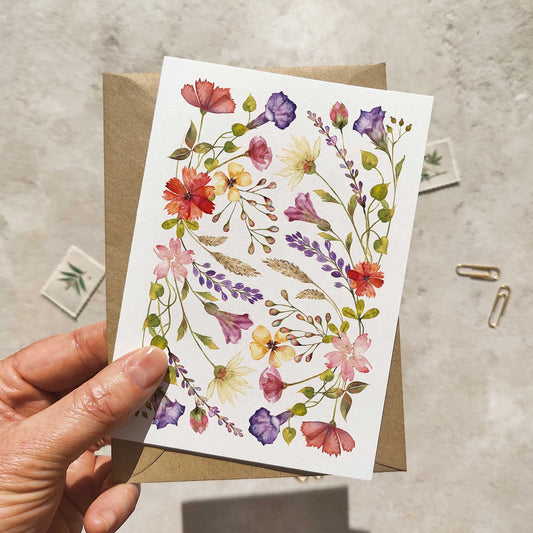 Hand holding a card with colorful floral design on a textured surface