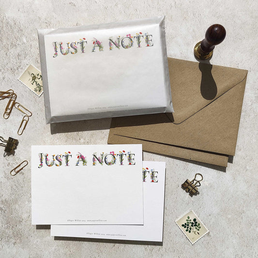 Stationery set with 'Just a Note' cards and an envelope on a textured surface.