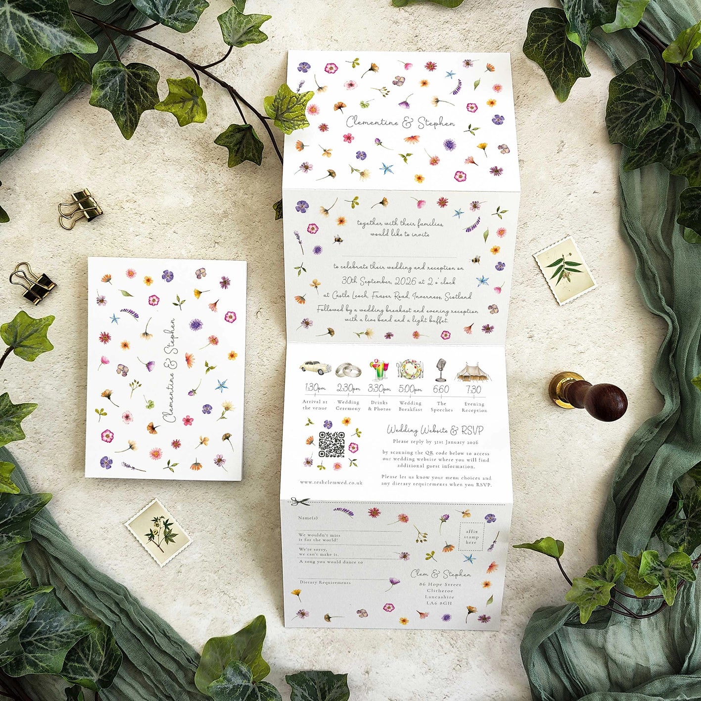 Wedding invitation set with floral design on a textured surface with greenery