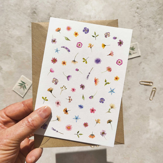 Hand holding a card with floral designs on a textured surface