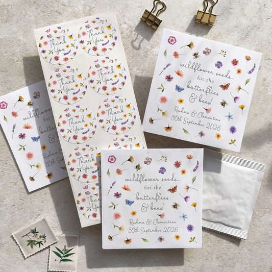 A collection of pressed wildflowers seed packets with floral designs, including personalized details such as names and dates. The packets are displayed on a textured surface with a butterfly and bee motif.