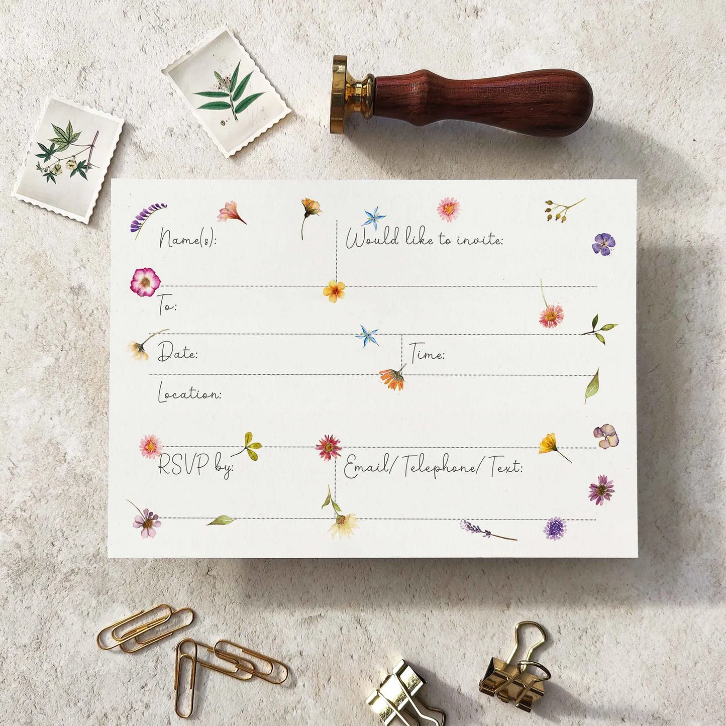 Floral invitation card with stationery items on a textured surface