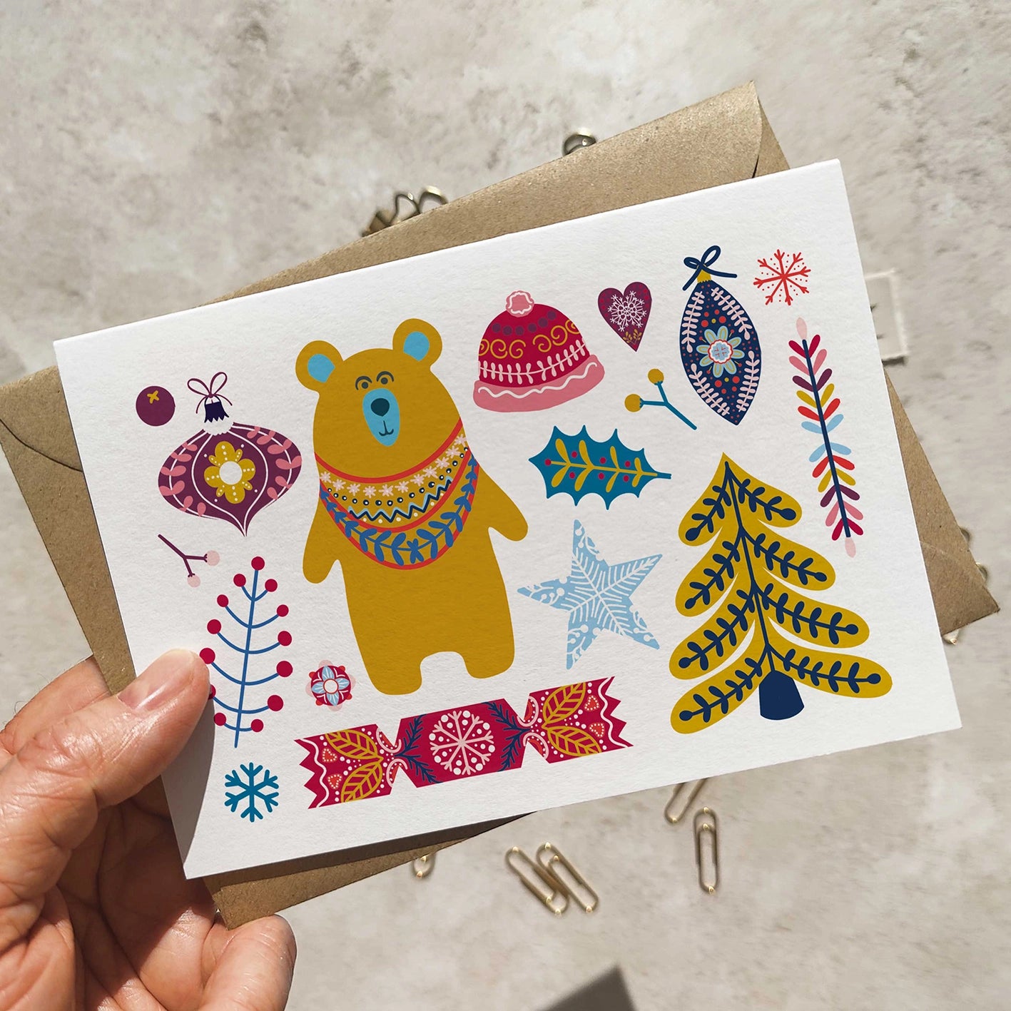 Colorful greeting card with a bear and festive elements held by a hand.