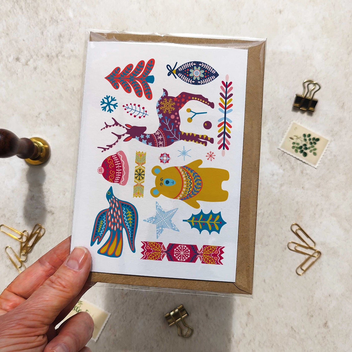 Hand holding a card with colorful animal illustrations on a textured surface.