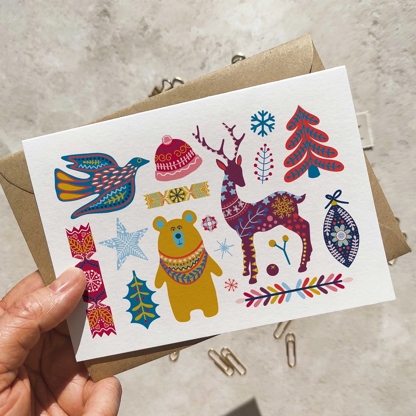 Colorful illustrated card with various patterns held by a hand on a neutral background