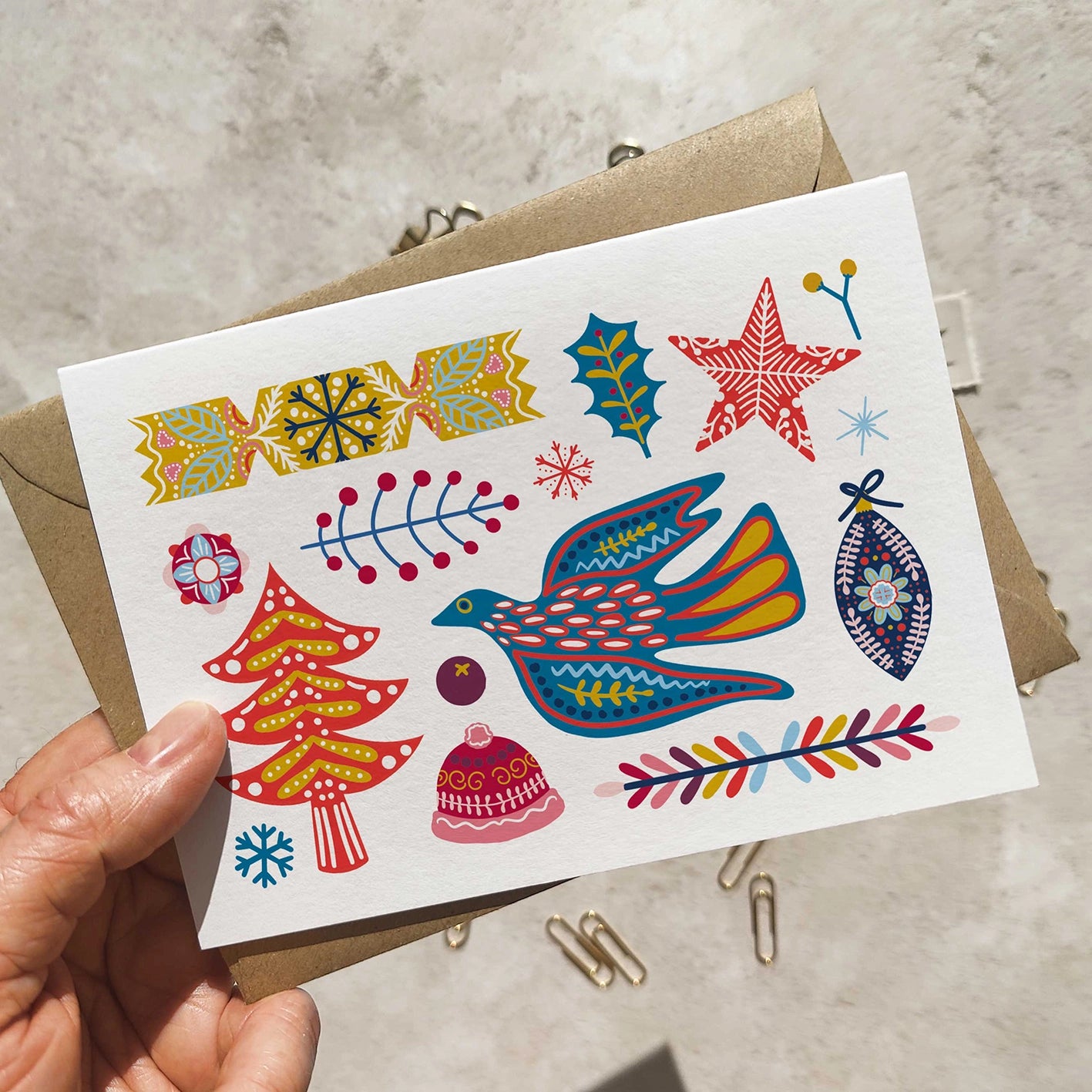 Colorful holiday-themed card held by a hand with a neutral background