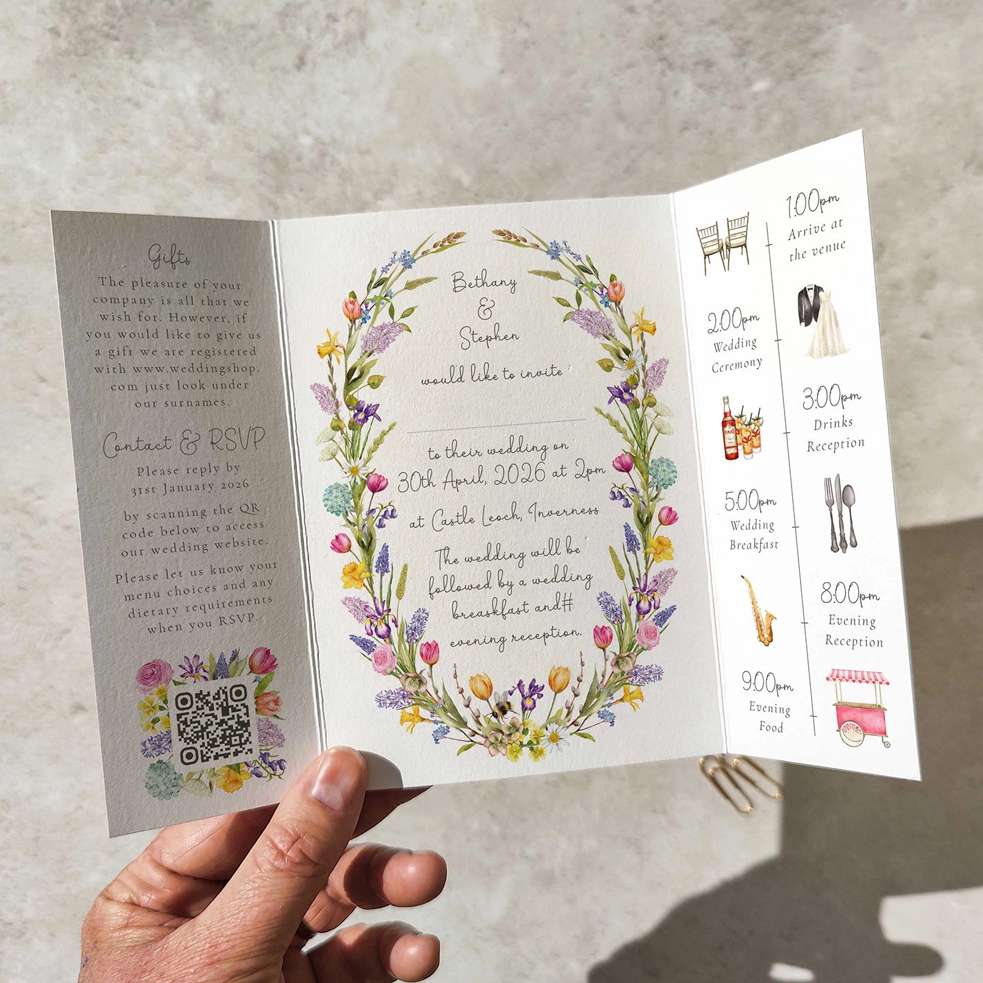 Hand holding a wedding invitation with floral design and event schedule.