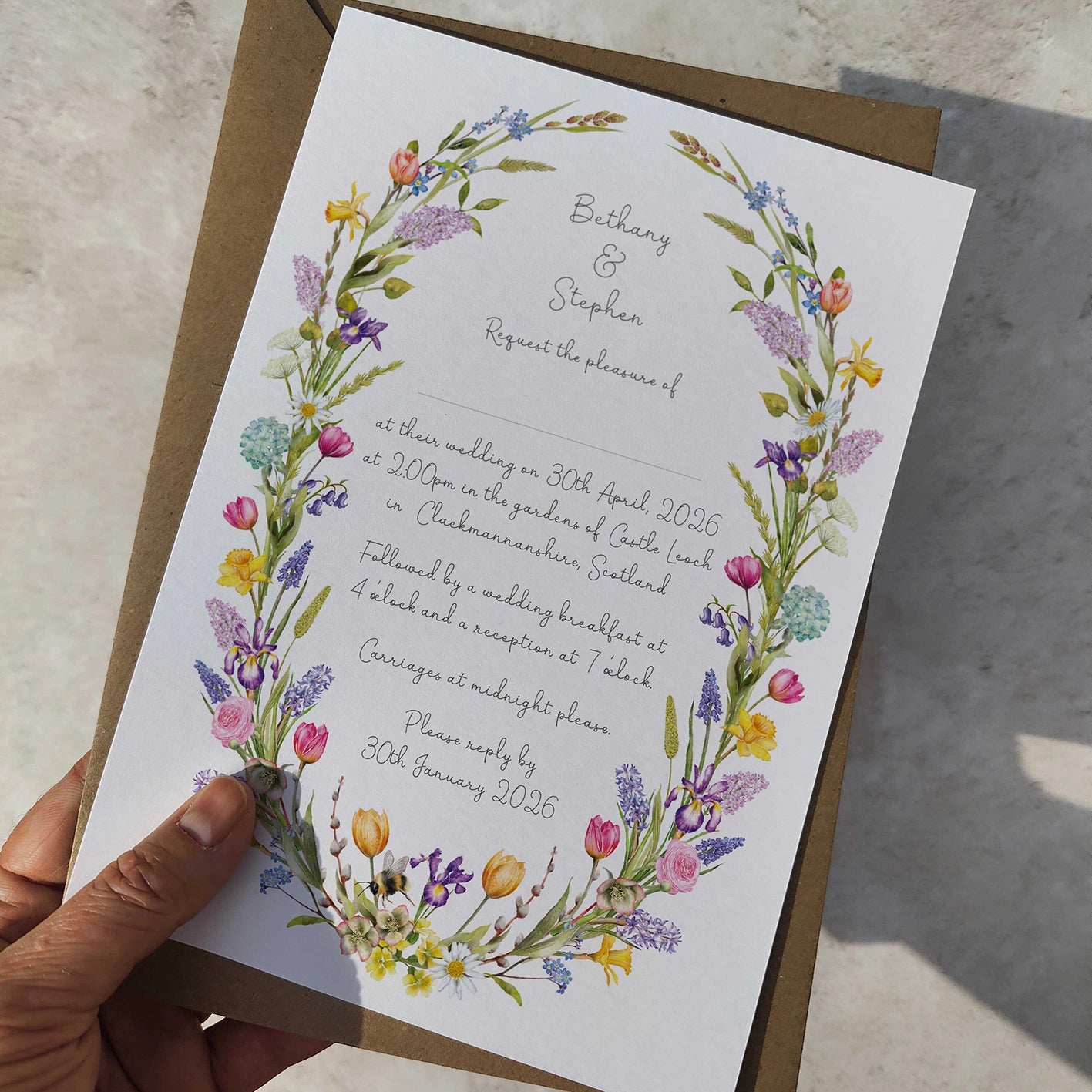 Wedding invitation with floral design held by a hand