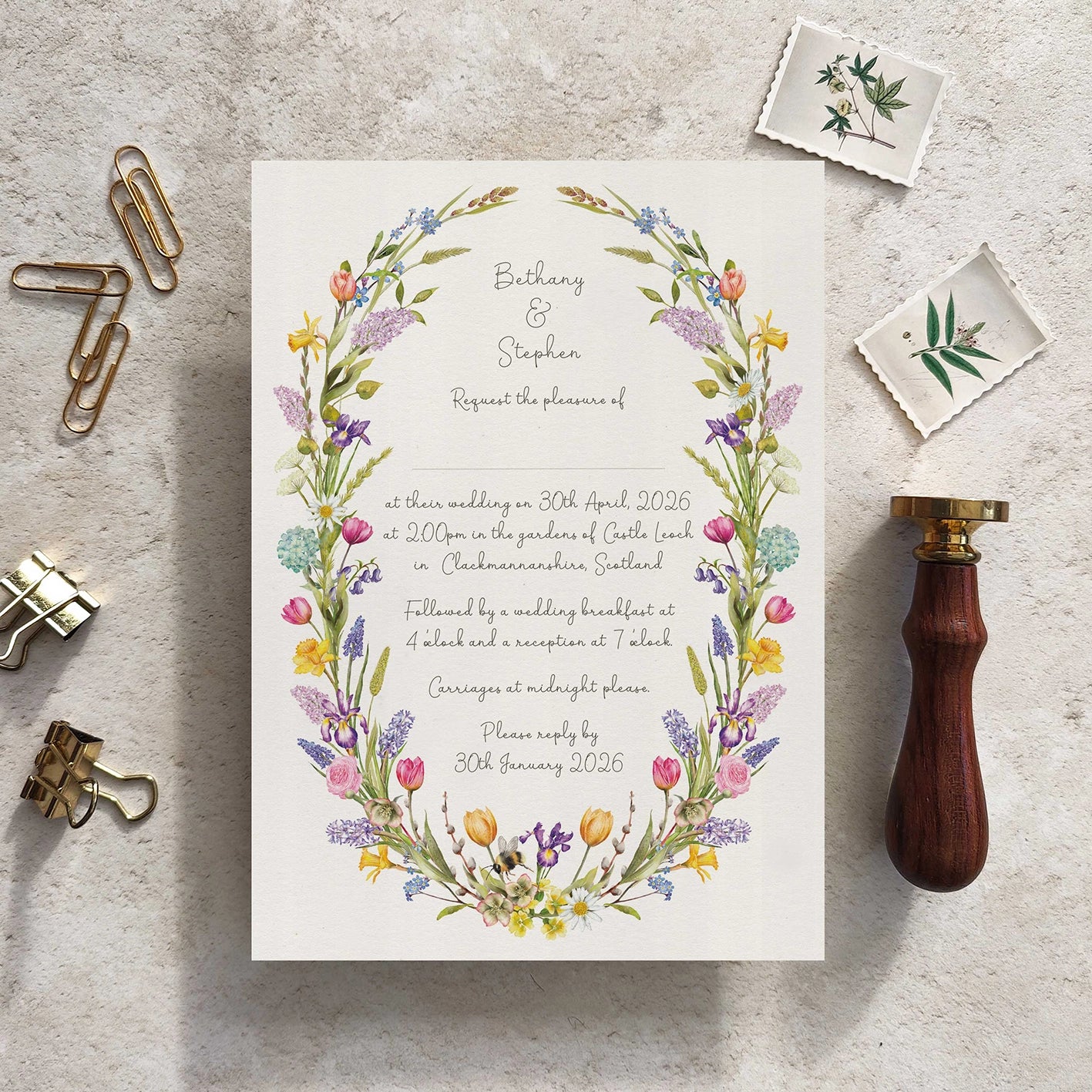 Wedding invitation with floral design on a textured surface with stationery items.