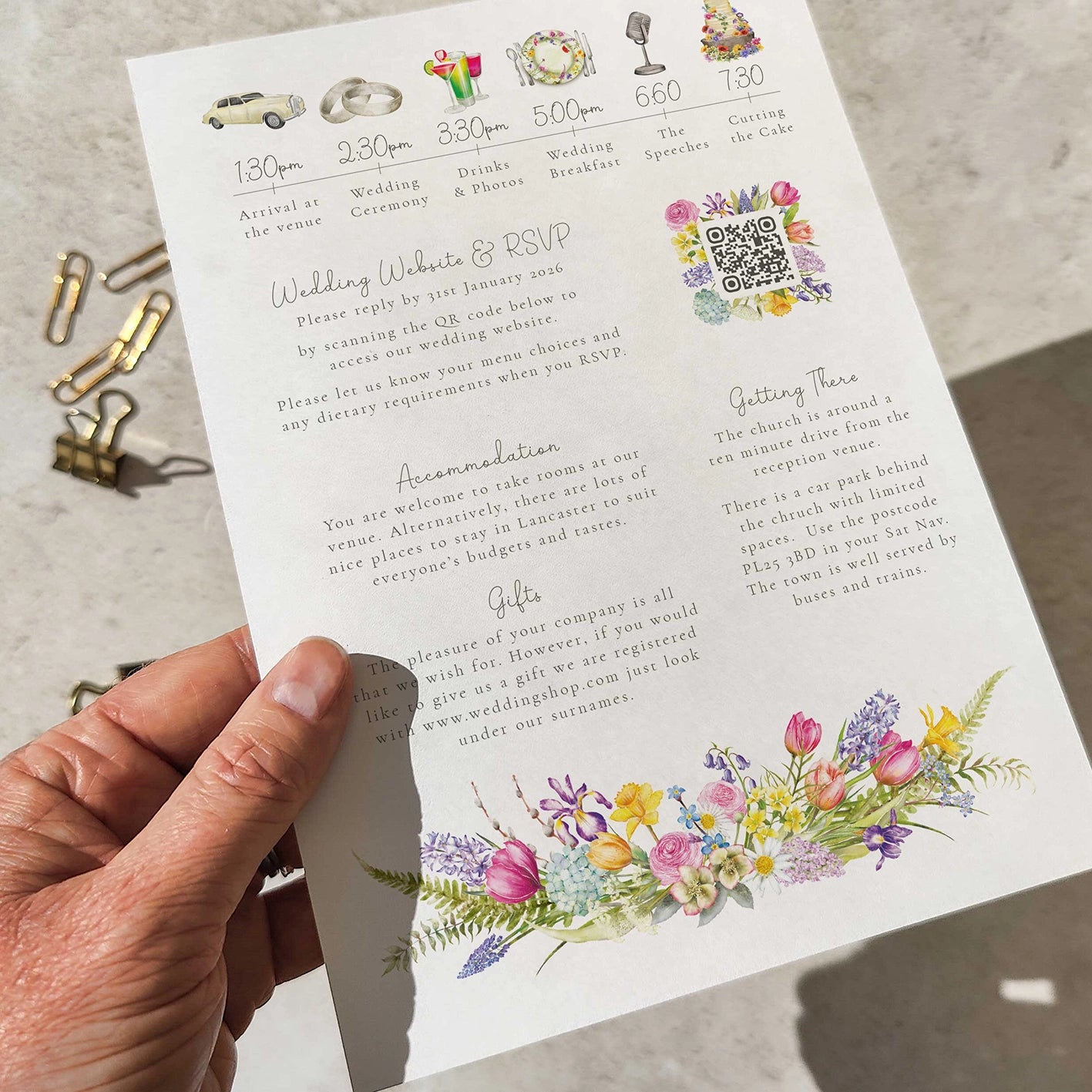 Hand holding a wedding invitation with floral designs and text.