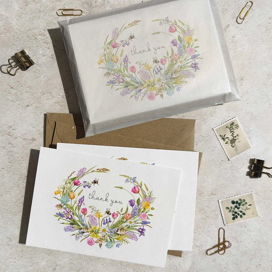 Two 'thank you' cards with spring themed floral designs on a textured surface.