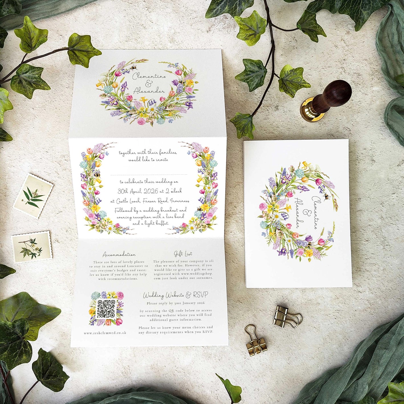 Wedding invitation set with floral wreaths and ivy leaves on a textured surface