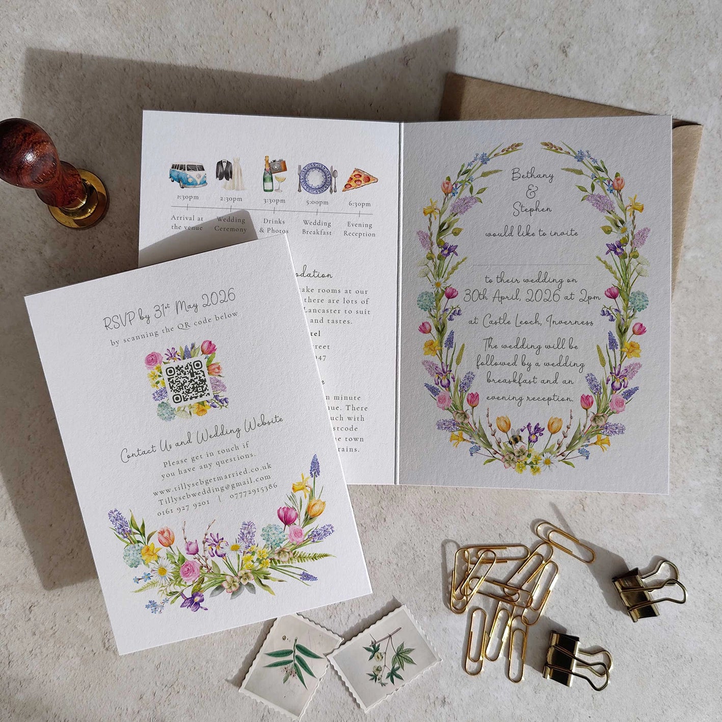 Floral wedding invitation set with RSVP QR code and stationery items on a textured surface.
