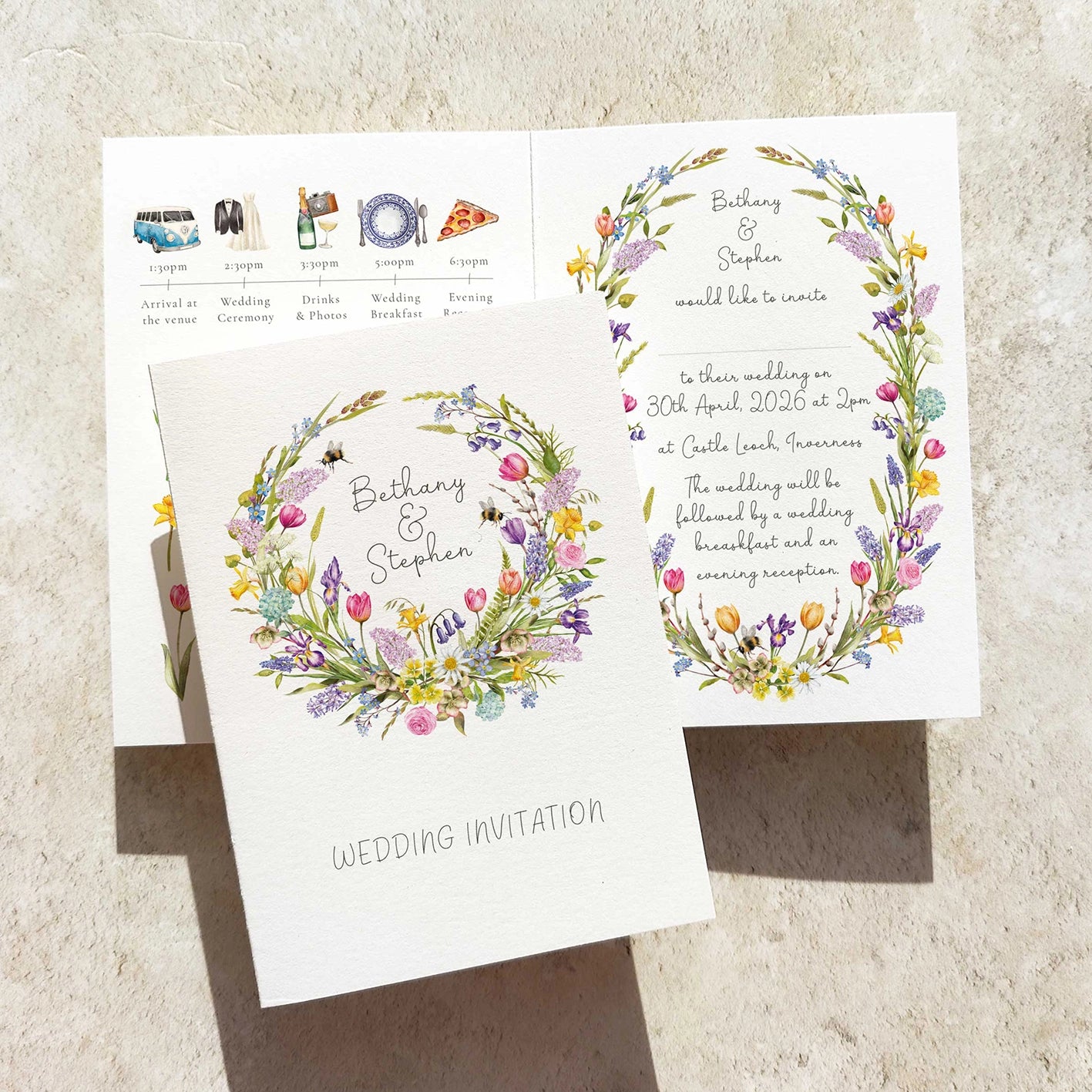 Wedding invitation card with floral wreaths on a textured surface