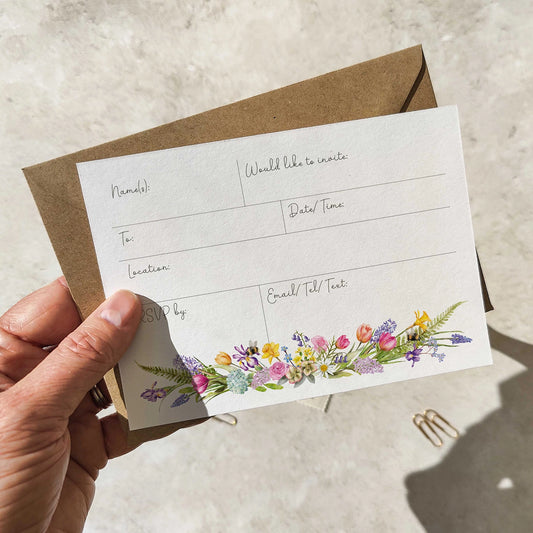 Hand holding a card with floral design and text fields on a neutral background
