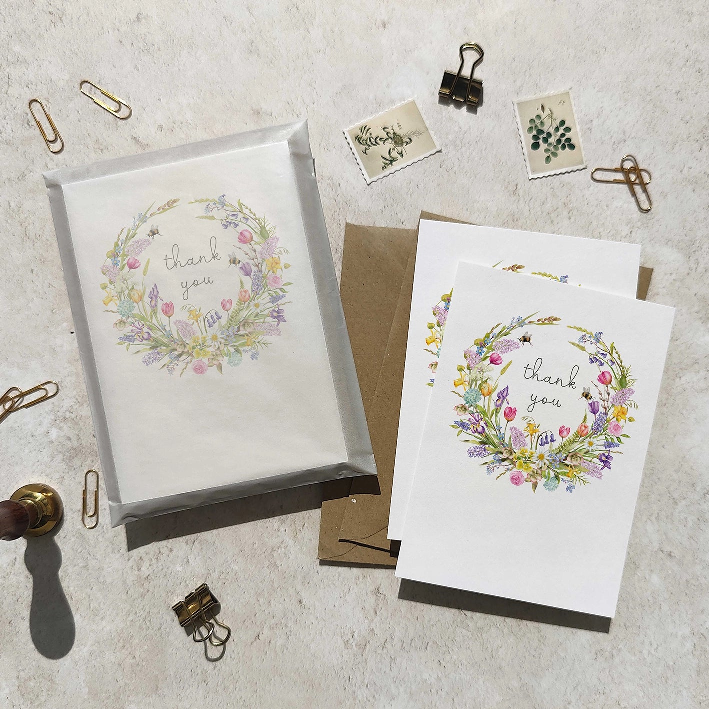 Set of greeting cards with floral wreath design and 'thank you' text on a textured surface.