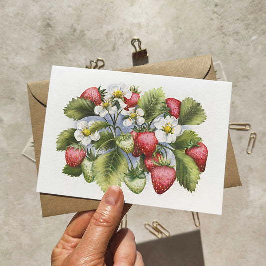 Card with strawberry illustration held by a hand against a textured background