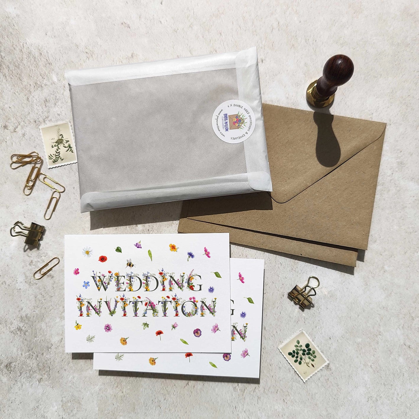 Wedding invitation card with envelope, sealing wax stamp, and decorative items on a textured surface