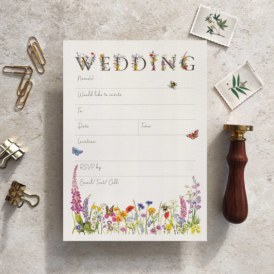 Wedding invitation card with floral design on a textured surface with stationery items.