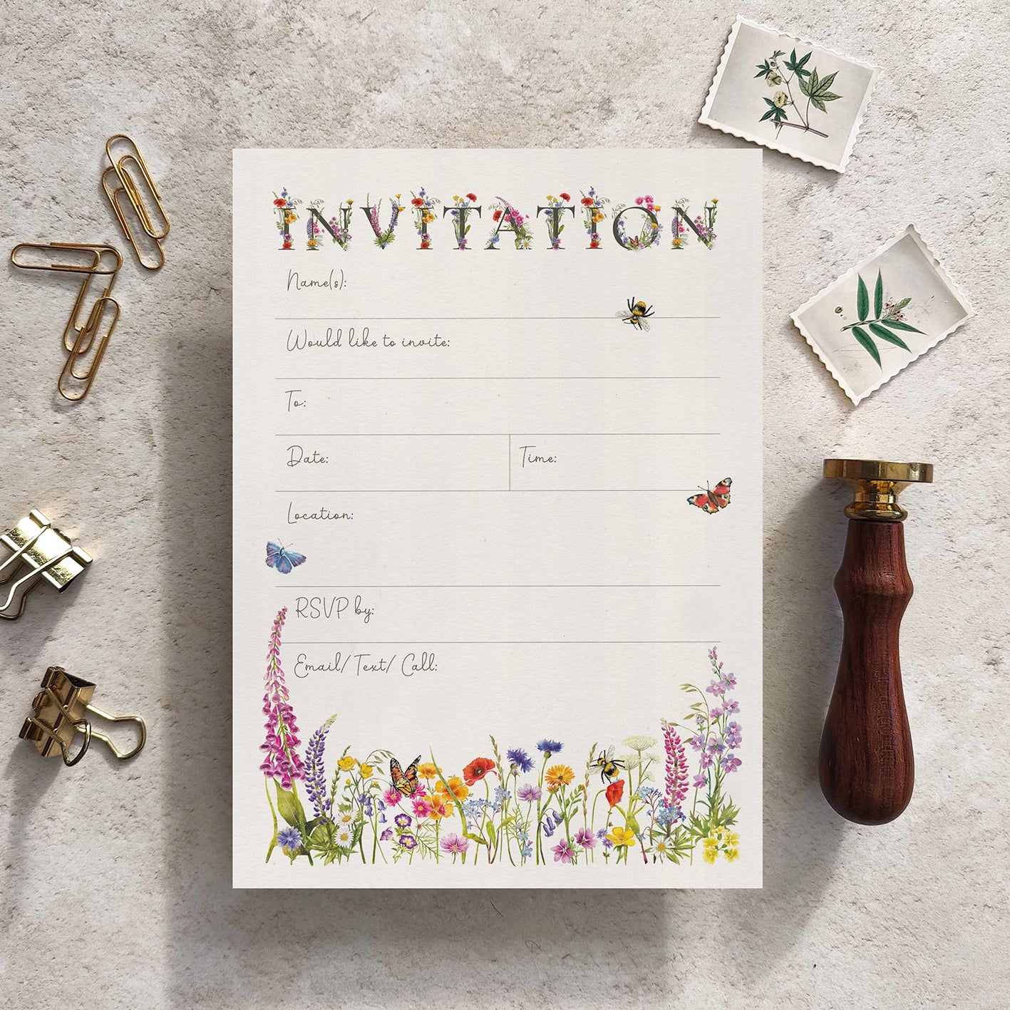 Invitation card with floral design on a textured surface with stationery items.