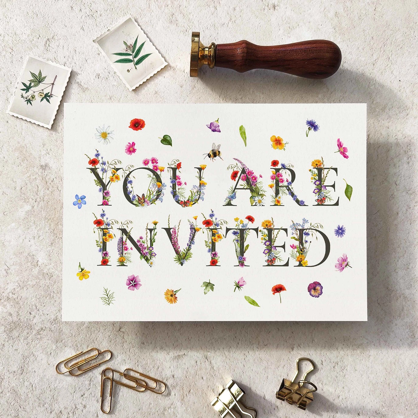 Card with 'You Are Invited' text surrounded by decorative items on a textured surface