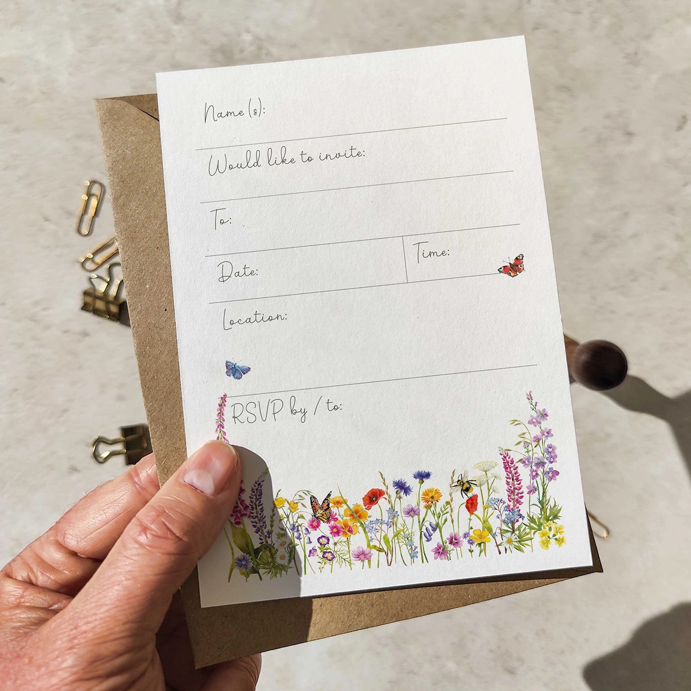 Hand holding a white card with floral design and text on a beige surface.