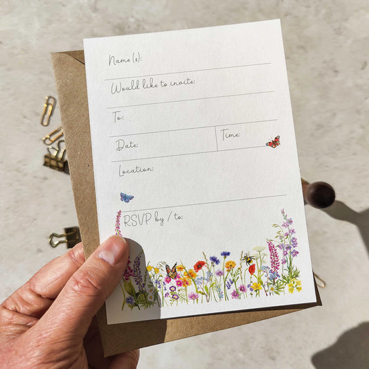 Hand holding a white card with floral design and text on a beige surface.