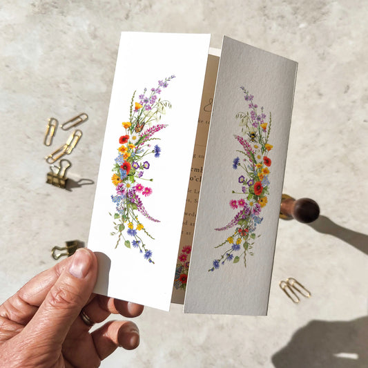 Hand holding a card with floral design on a textured surface