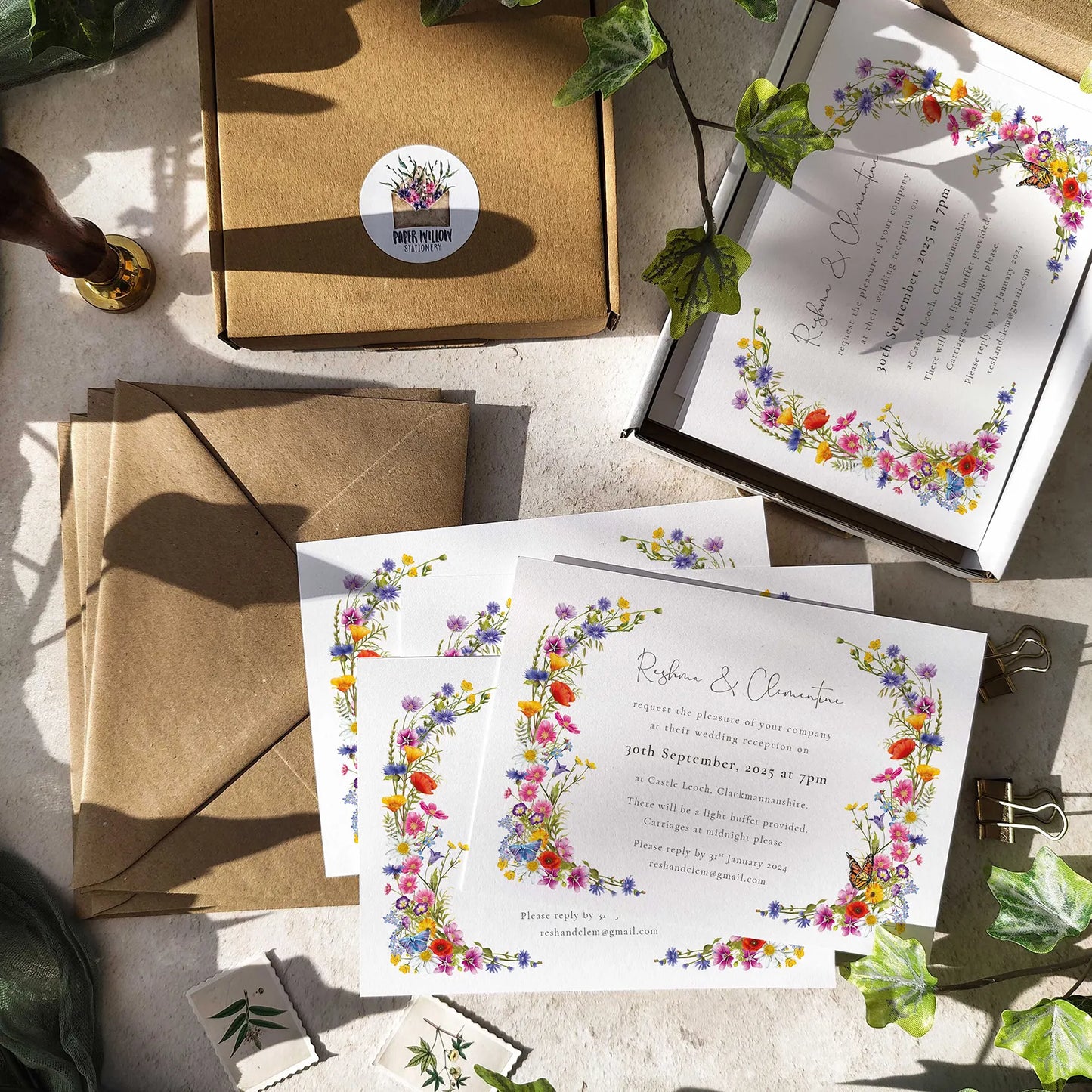 Wedding invitations with floral designs on a table with envelopes and a box.