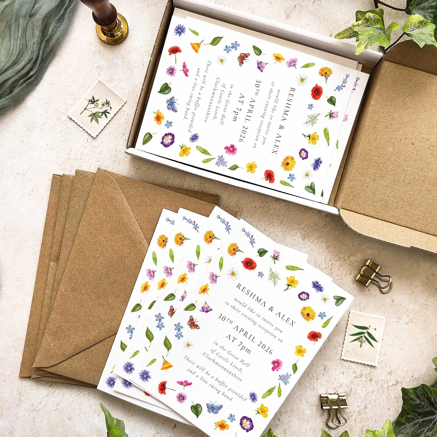 Floral wedding invitations with matching envelopes on a light surface.