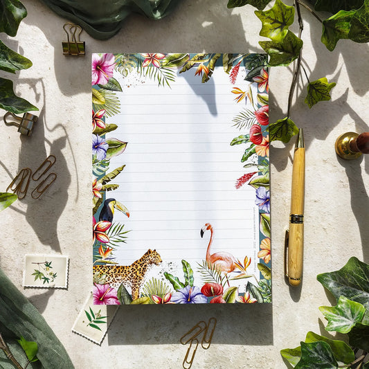 Floral and animal-themed notepad with stationery items on a textured surface.