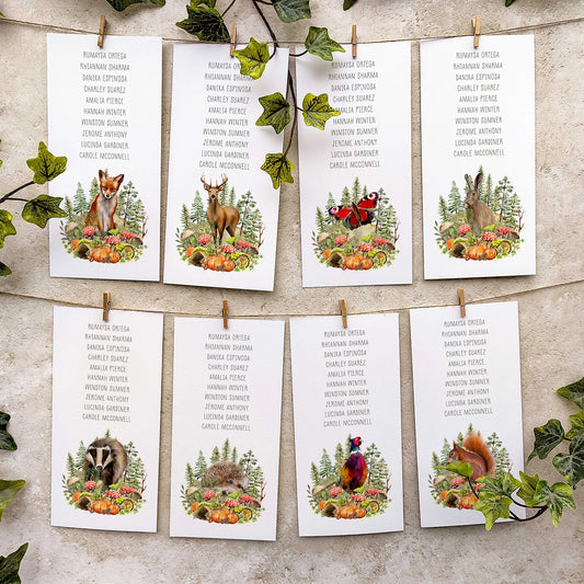 Set of table plan cards with autumn forest animals and plants on a textured surface.