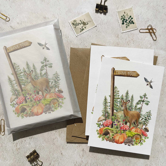 Set of greeting cards with nature-themed designs featuring deer and autumn elements on a textured surface.