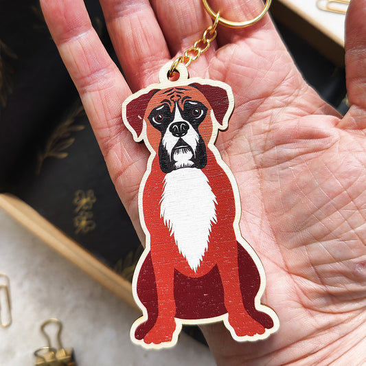 Wooden keychain shaped like a boxer dog held in a hand