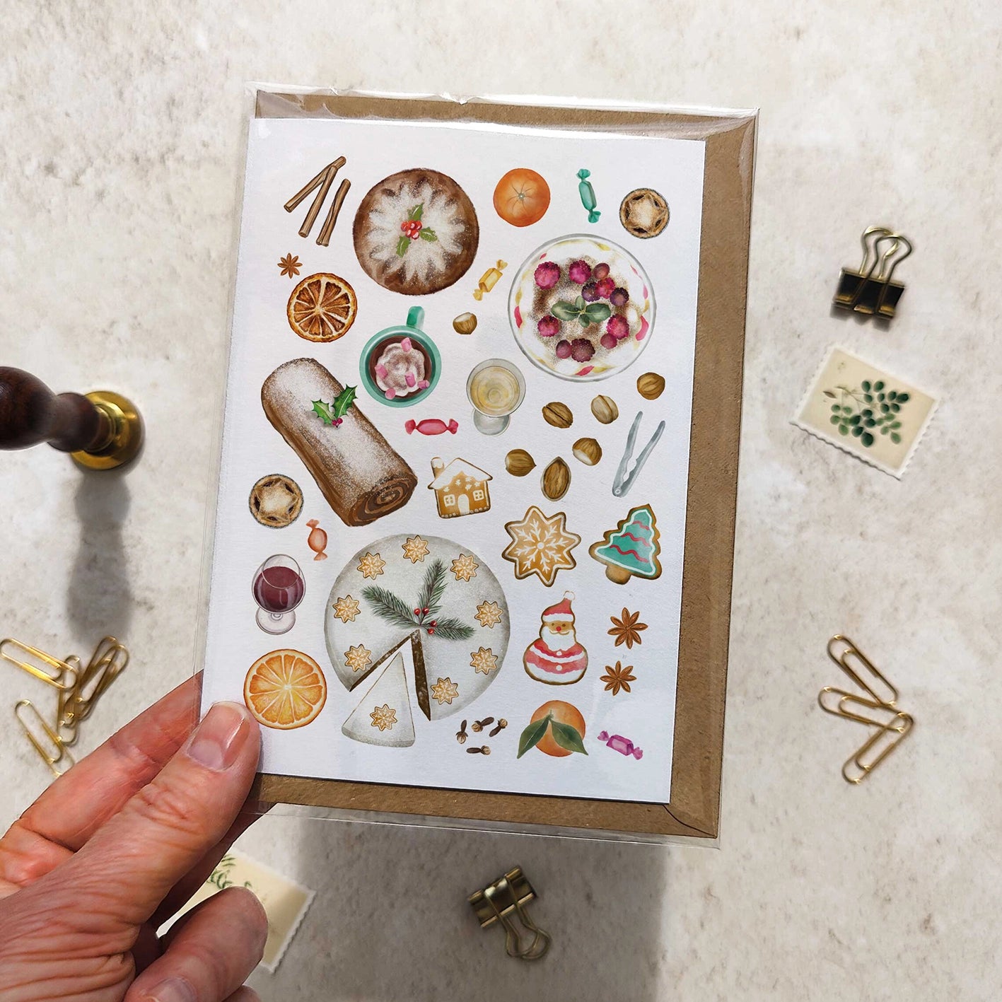 Hand holding a card with festive illustrations on a textured surface.