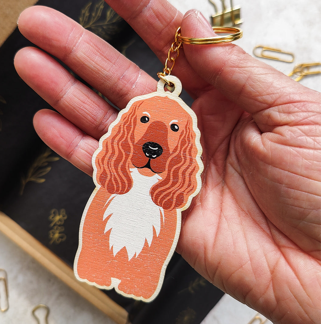 Hand holding a keychain with a cocker spaniel dog design on a blurred background