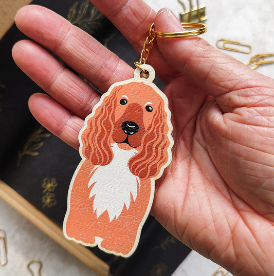 Hand holding a keychain with a cocker spaniel dog design on a blurred background
