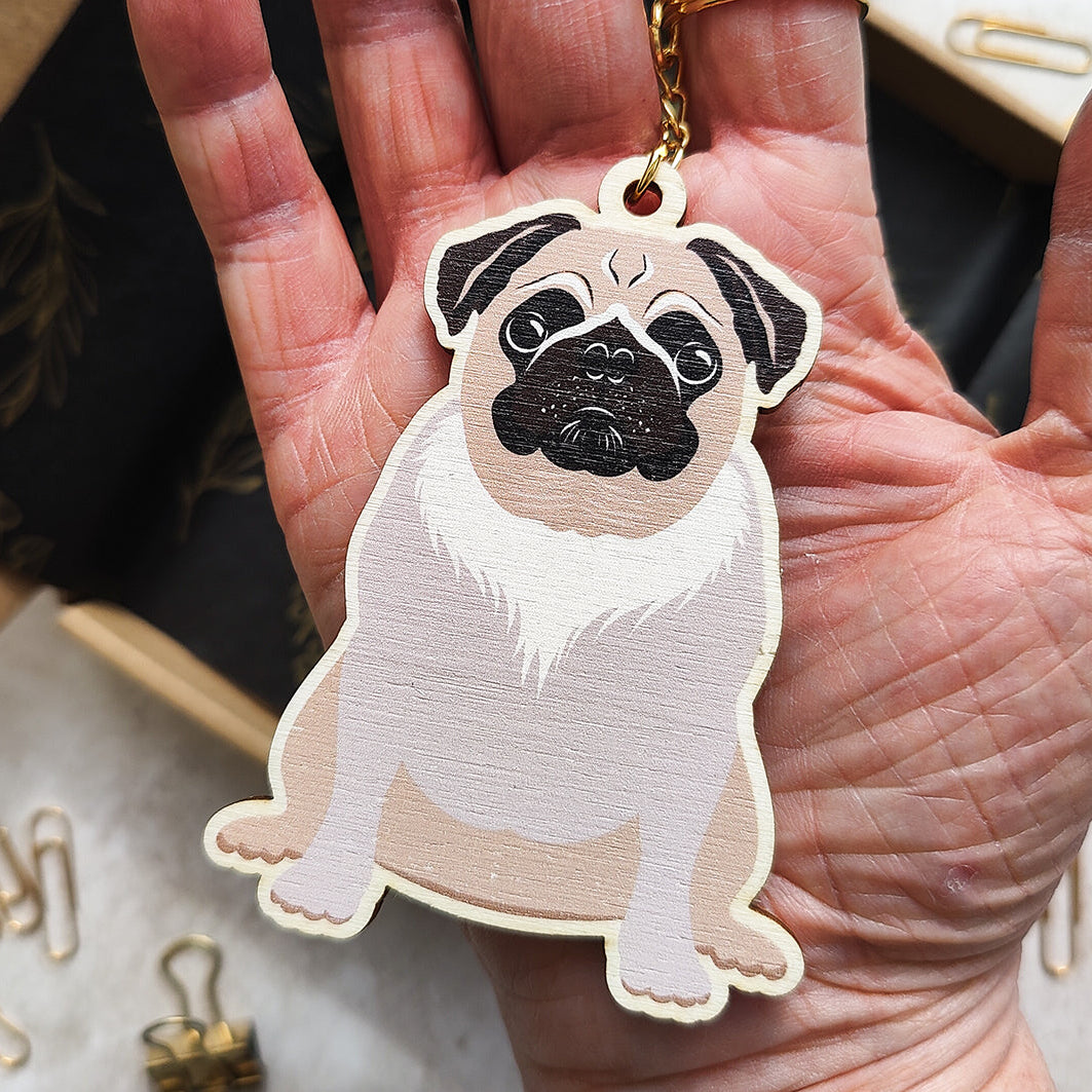Hand holding a pug-shaped keychain with a blurred background