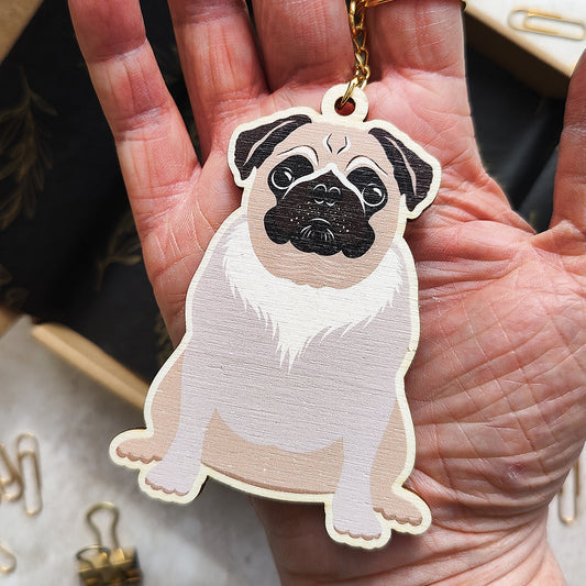 Hand holding a pug-shaped keychain with a blurred background