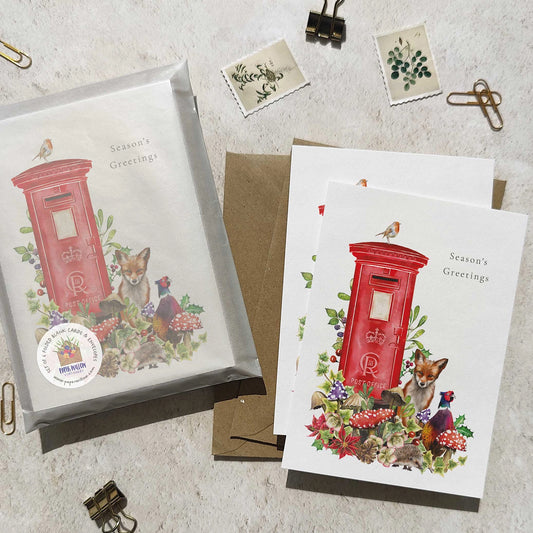 Set of greeting cards with red postbox design and 'Season's Greetings' text on a textured surface.