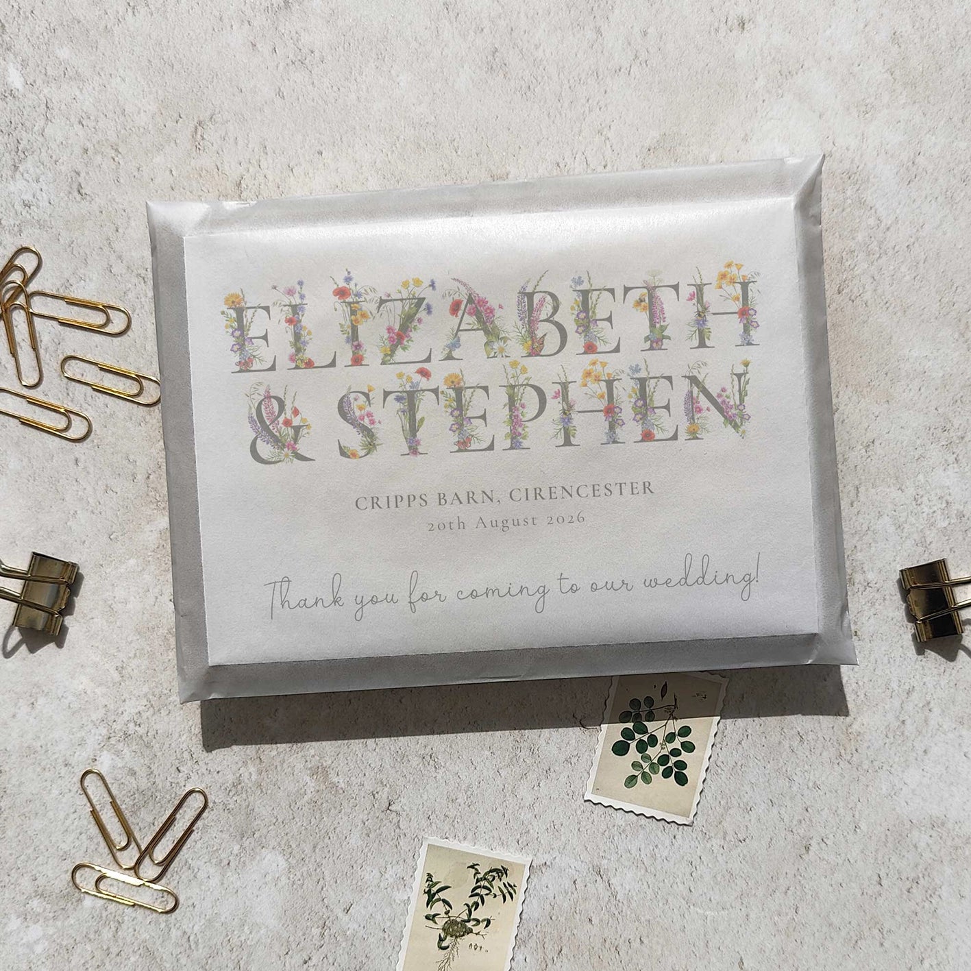 Wedding thank you cards with floral text on a textured surface with paper clips.