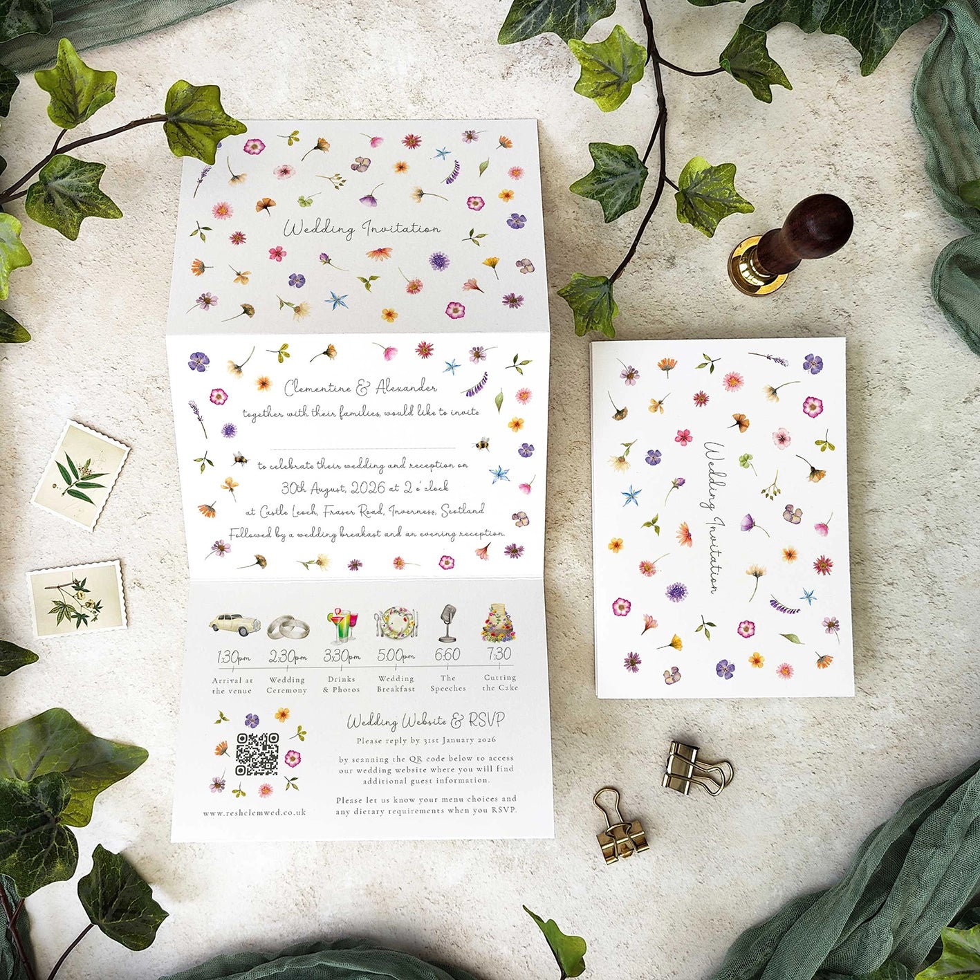 Floral wedding invitation set with stationery items on a textured surface.