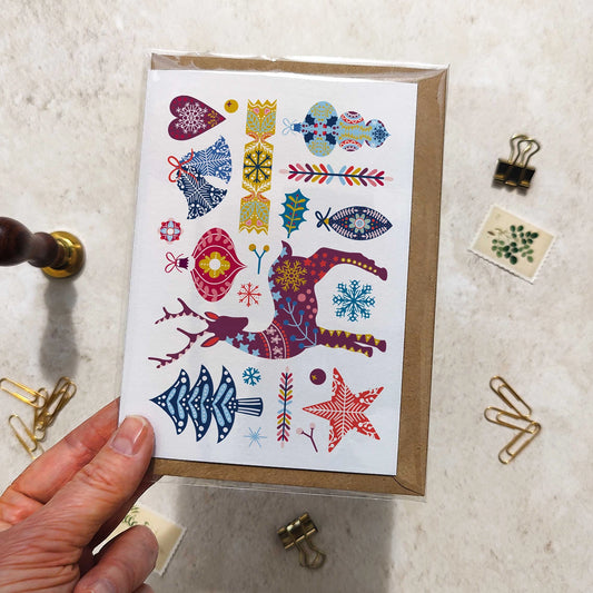 Card with colorful patterns held by a hand on a textured surface with office supplies.