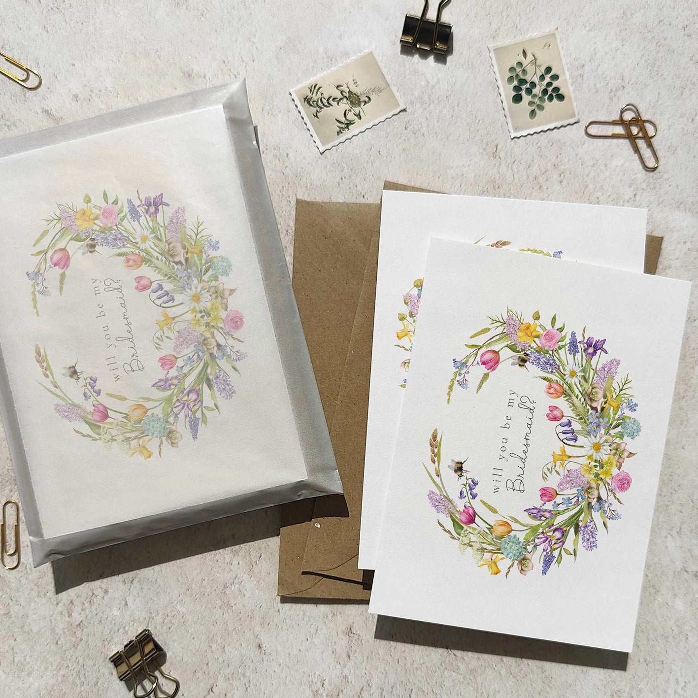 Floral wreath bridesmaid cards with envelopes on a textured surface