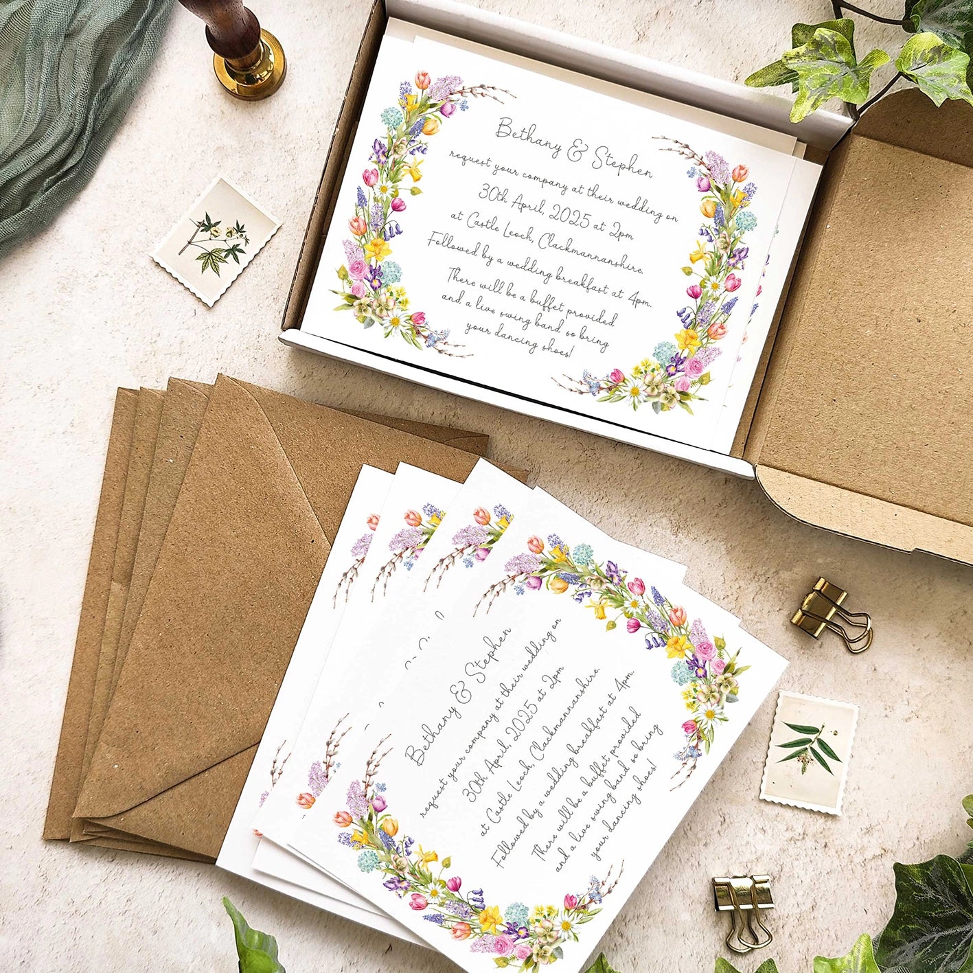 Wedding invitations with floral designs on a textured surface with envelopes and stationery items.