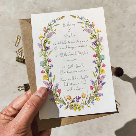 Hand holding a wedding invitation card with floral design on a neutral background