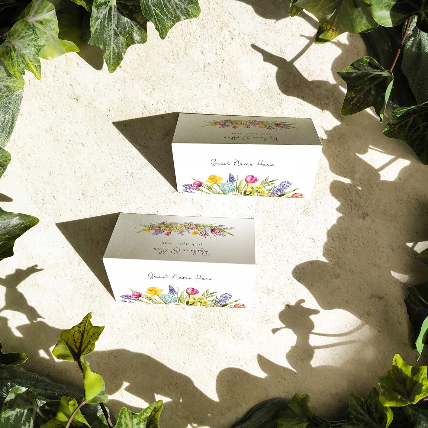 Set of floral place cards on a textured surface with green leaves around